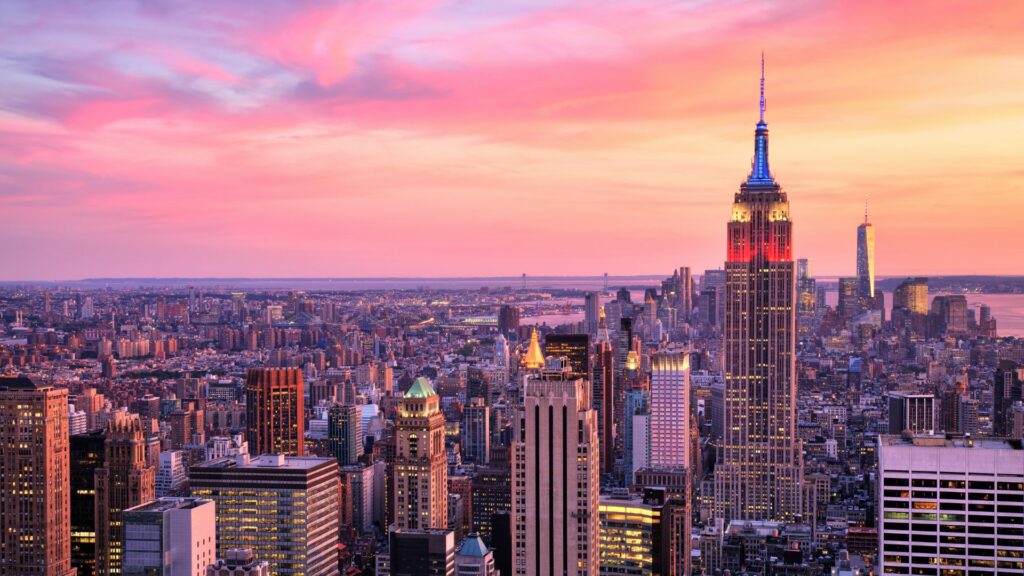 Vue panoramique de Manhattan au coucher du soleil avec l'Empire State Building au centre.