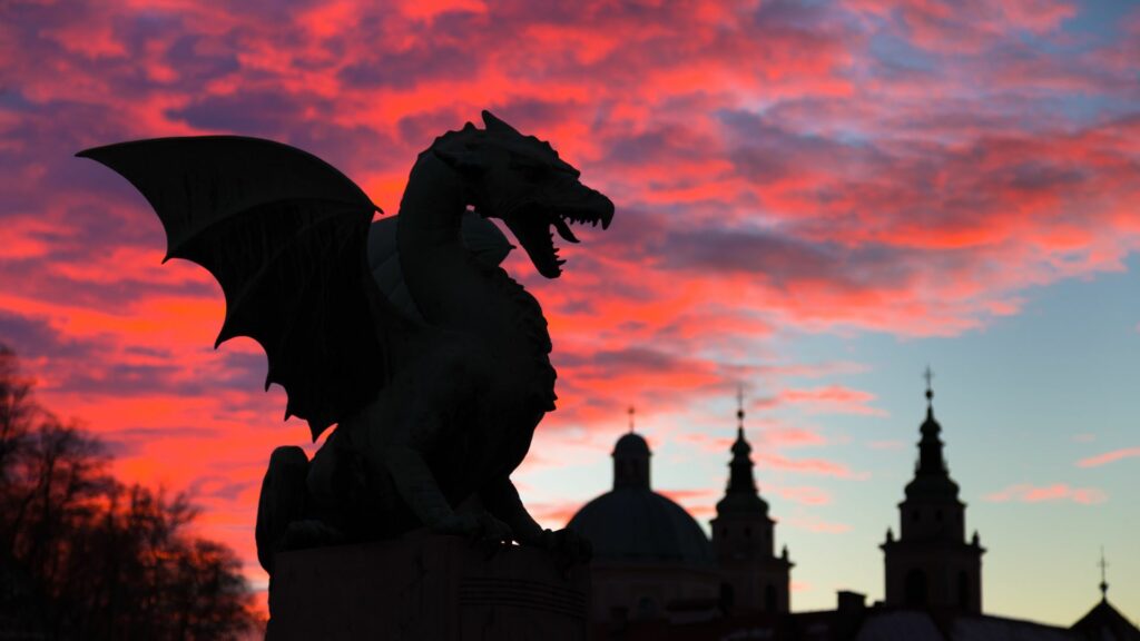 Statue de dragon à Ljubljana au coucher du soleil avec un ciel rouge et violet.