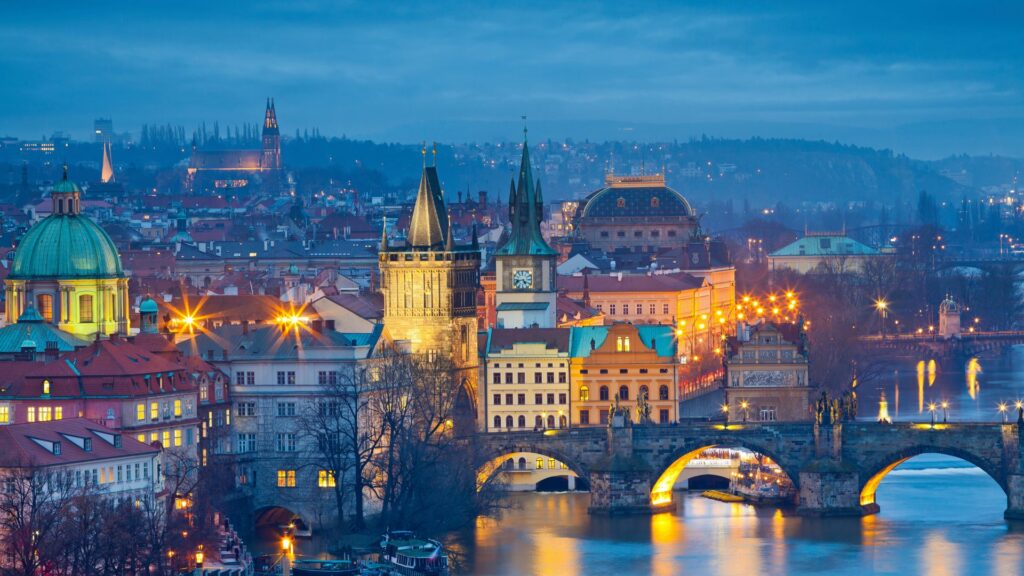 Vue de Prague de nuit avec le pont Charles illuminé et les toits de la vieille ville.